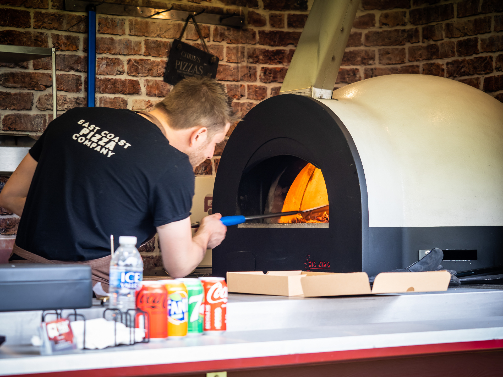 Chris sliding a pizza into the wood-fired oven inside the Nag Box
