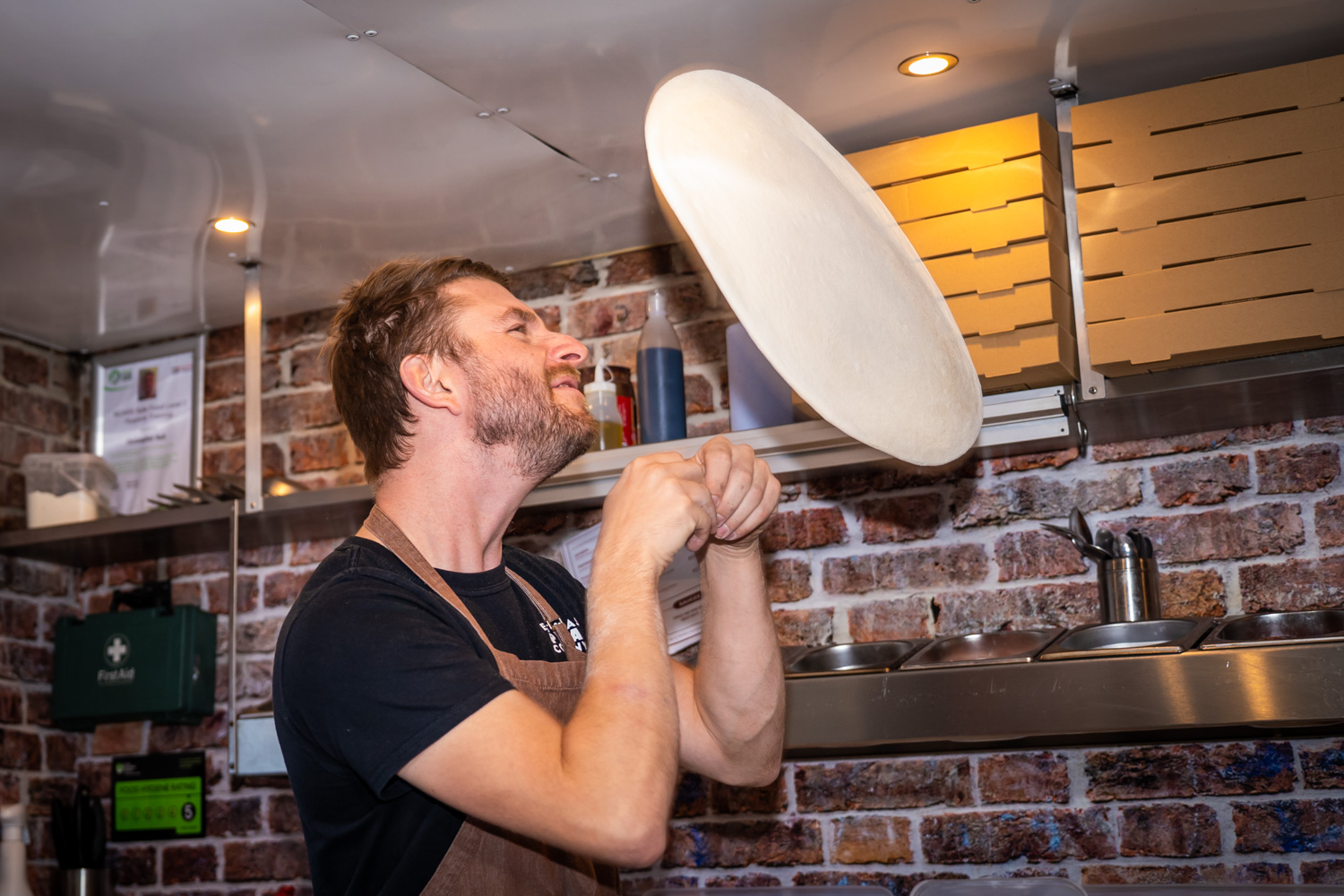 Chris tossing a pizza dough mid-air inside the Nag Box