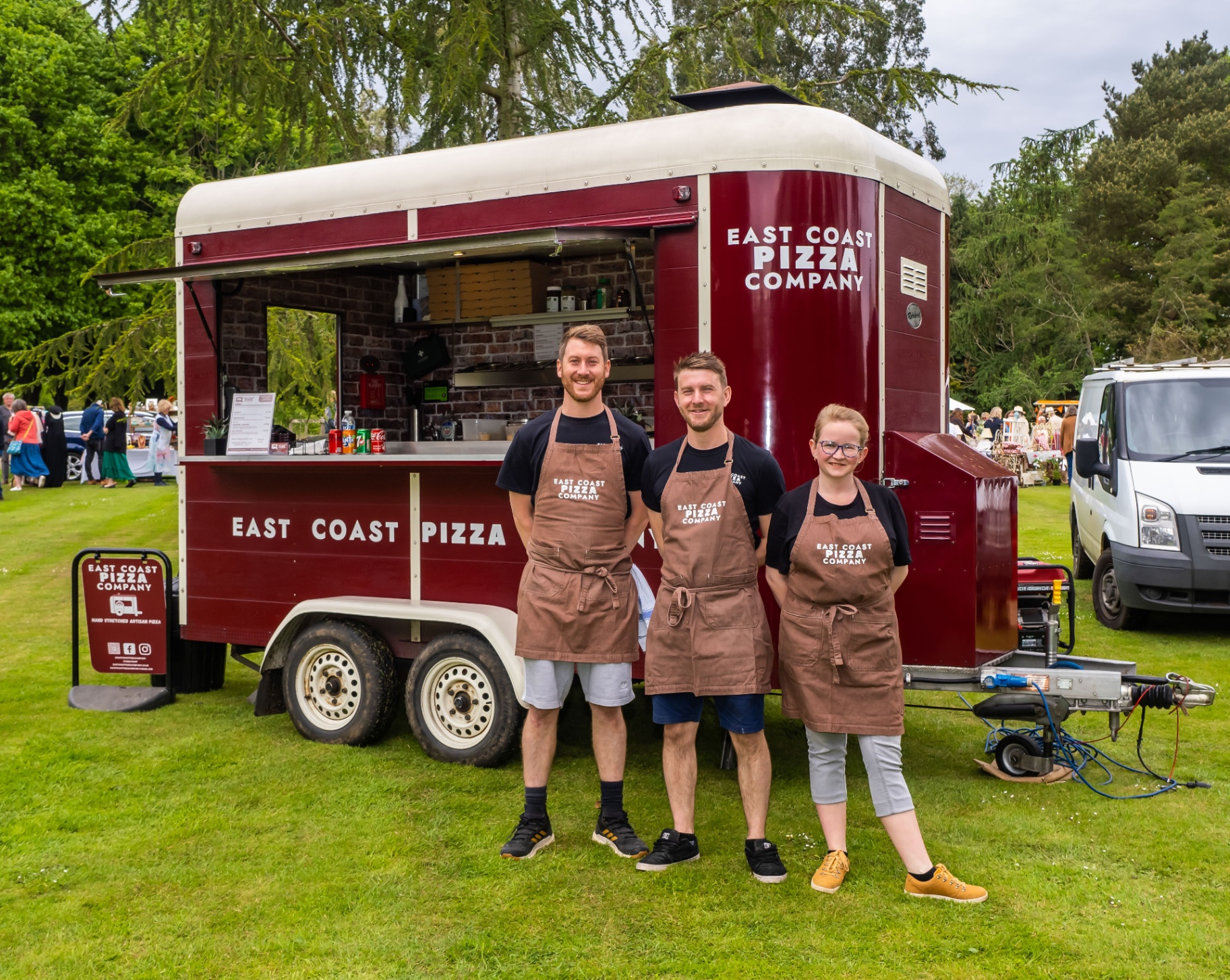The full East Coast Pizza team standing in front of the red Nag Box trailer at a country event