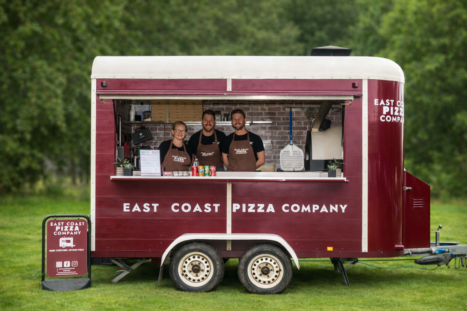 The Nag Box parked in a green field with three smiling team members at the hatch