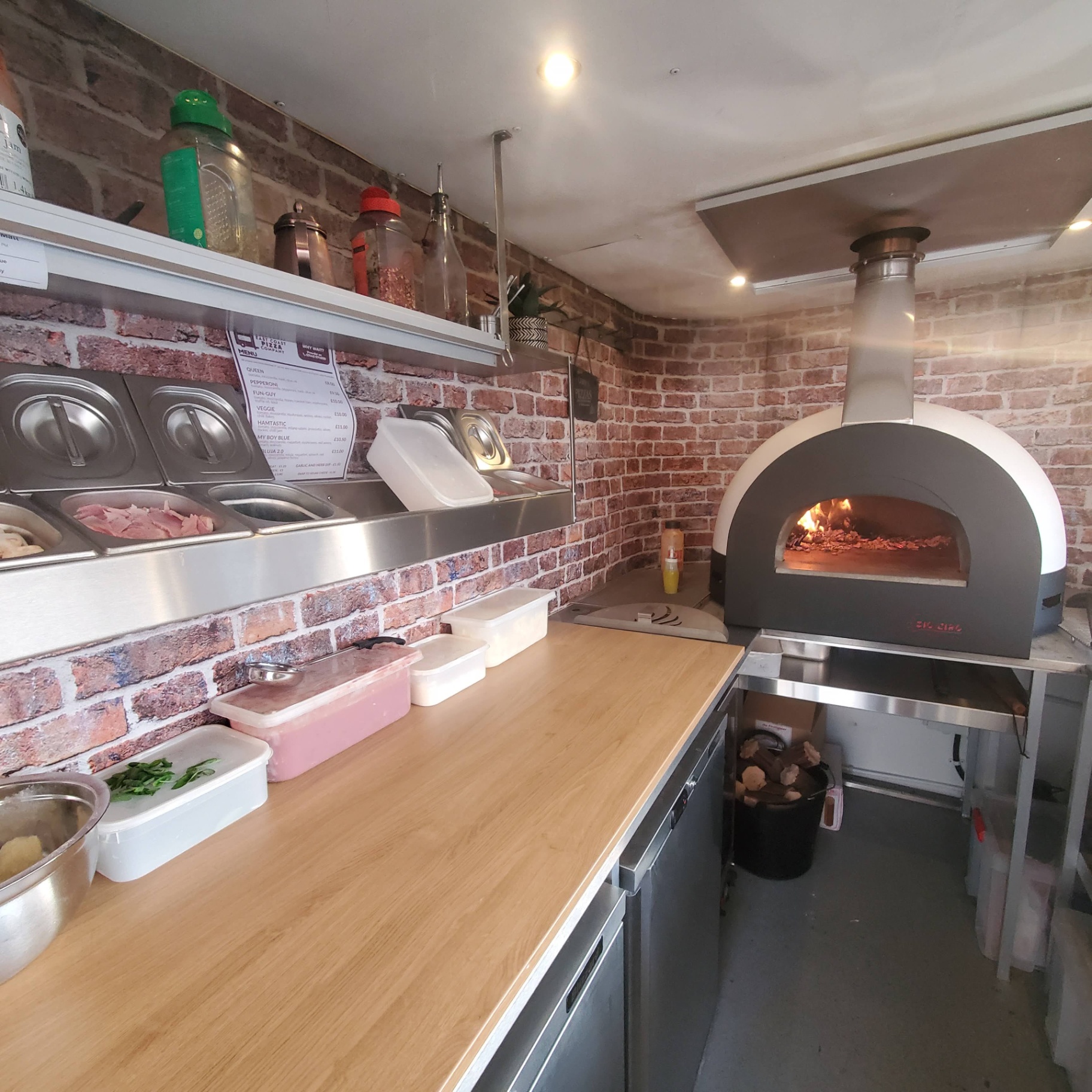 Inside the Nag Box — wood-fired oven, prep counter and menu